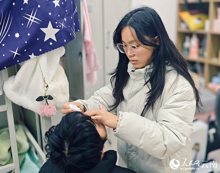 【1】陆佳慧（右）帮助小燕点眼药水。人民网 尹馨摄